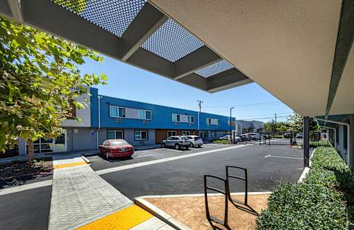 A parking lot with a red car and a blue building in the background.