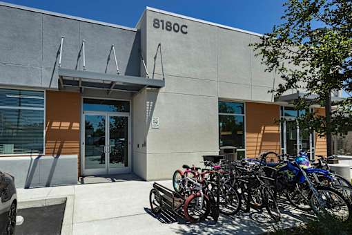 A building with the number 6180C on it has bicycles parked outside.