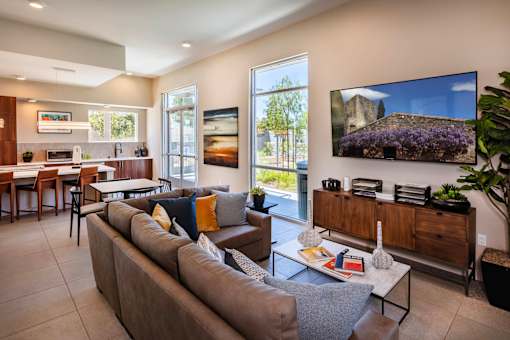 A living room with a grey couch and a flat screen TV mounted on the wall.