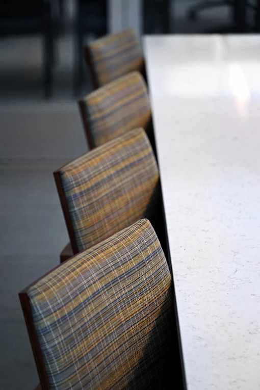 A row of brown plaid chairs are lined up against a white wall.