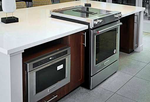 A modern kitchen with a white countertop and stainless steel appliances.