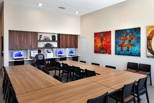 A conference room with a long table and chairs, and paintings on the wall.