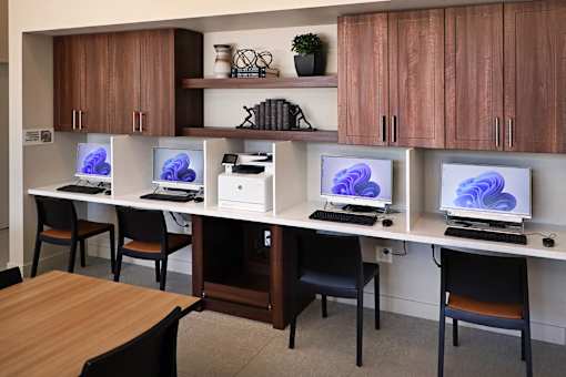 A room with a desk and chairs with a computer on it.
