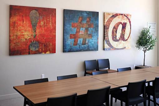 A conference room with a long table and three paintings on the wall.