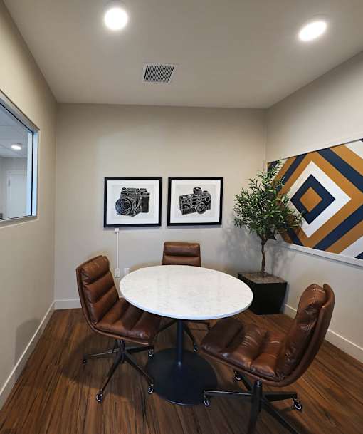 A conference room with a white table and brown chairs.