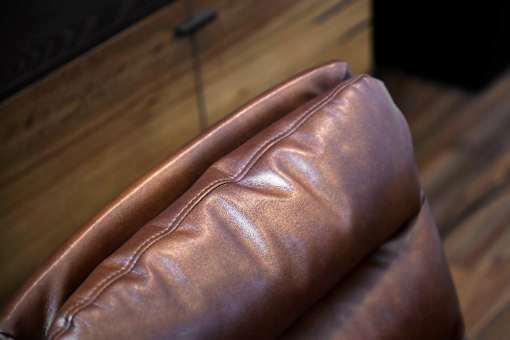 A brown leather couch with a wooden background.