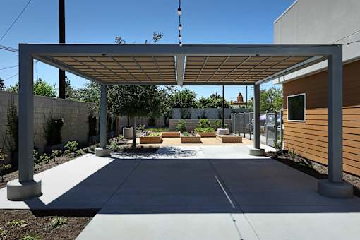 A patio with a white pergola and concrete floor.