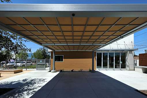 A building with a brown exterior and a white roof with a metal frame.