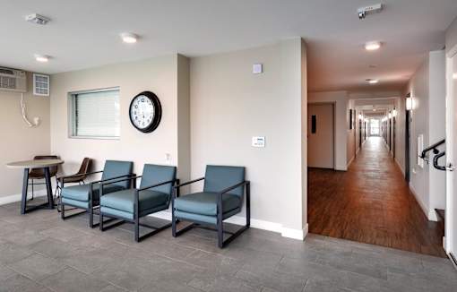 A waiting room with four chairs and a clock on the wall.