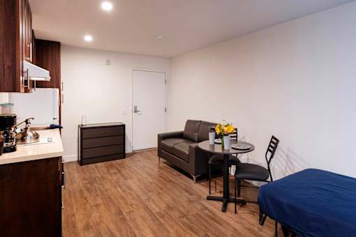 A kitchen with a refrigerator, a table with a blue tablecloth, and a couch.