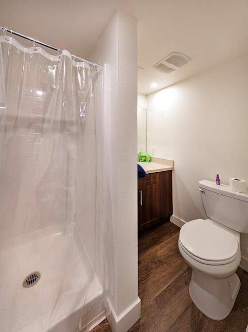 A white toilet in a bathroom with a white shower curtain.