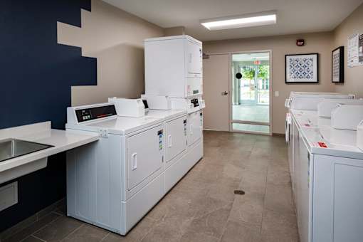 A clean, modern kitchen with white appliances and a tiled floor.