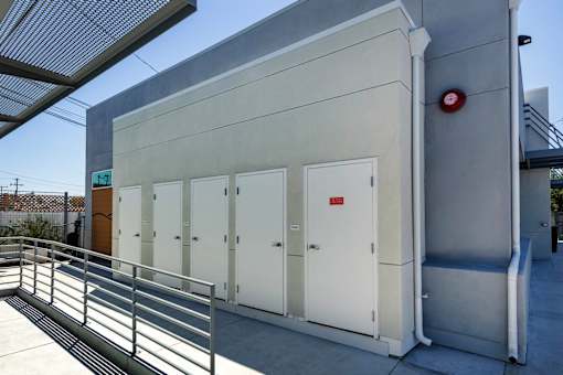A small building with a red circle on the wall and a metal railing in front.