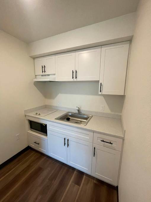 A kitchen with white cabinets and a wooden floor.