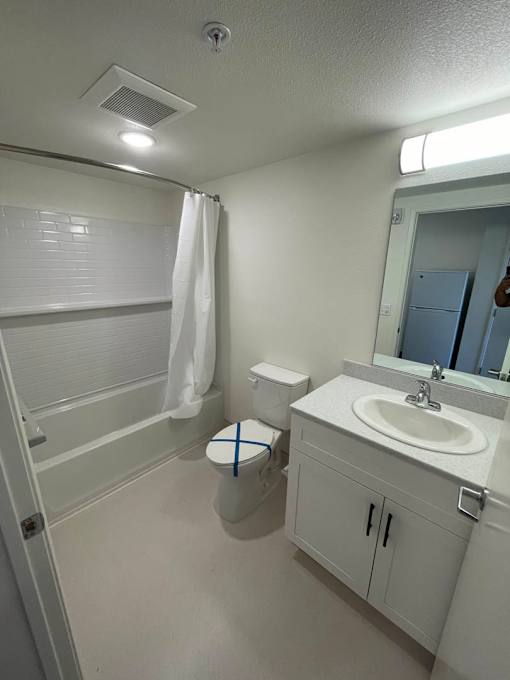 A white bathroom with a toilet, sink, and shower.