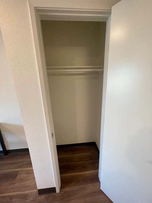 A white door is open to a room with a wooden floor.