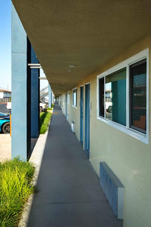 A long, narrow building with a blue trim and white walls.
