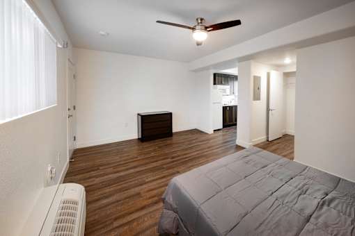 A bedroom with a bed, a ceiling fan, and a window with blinds.
