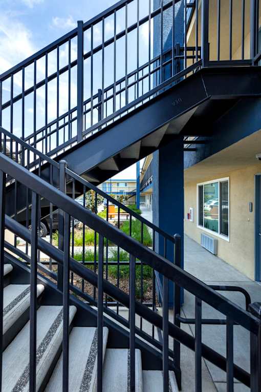 A staircase with a metal railing and steps leading to a door.