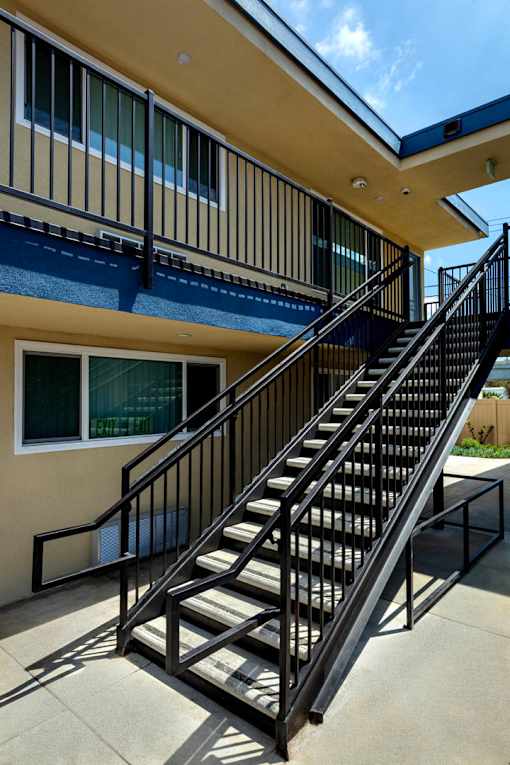 A staircase with a metal railing leads up to a balcony.