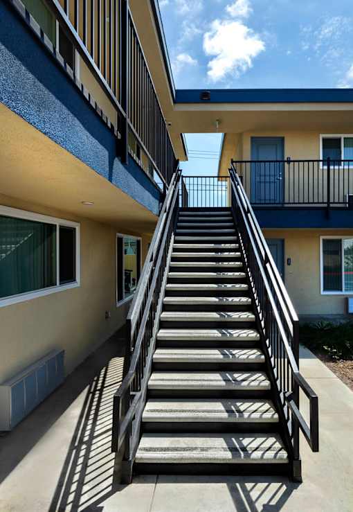 A staircase with a metal railing leads up to a balcony.