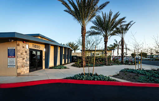 The image shows a building with the number 11850 on it, surrounded by palm trees and a clear sky.