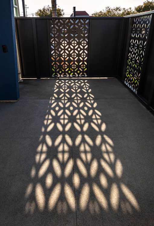 A shadow of a decorative fence is cast on the ground.