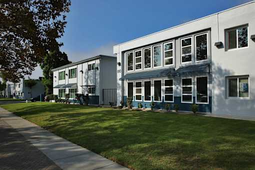A white building with a blue trim is surrounded by a green lawn.