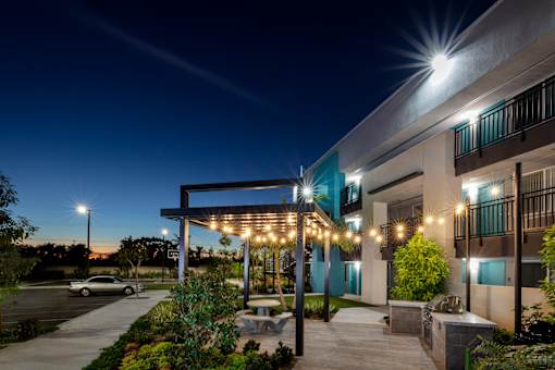 A building with a covered walkway and lights is shown at night.