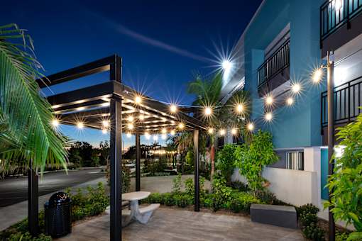 A patio area with a table and chairs under a lit pergola.