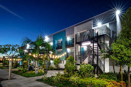 A modern building with a staircase and lights on the trees.
