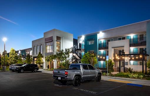 A parking lot with a silver truck and a black car.