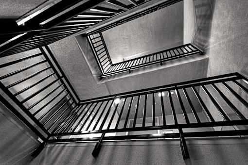 A black and white image of a staircase with metal railings.