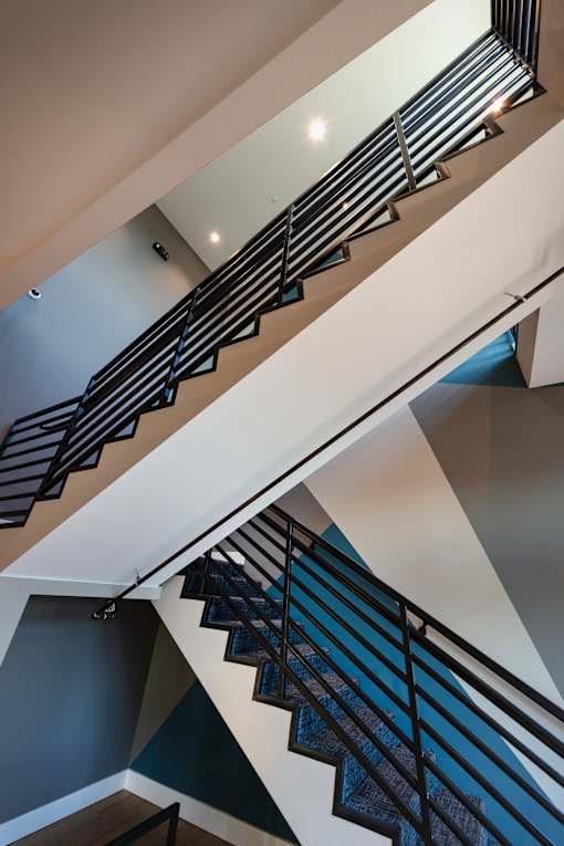 A staircase with a metal railing and a wooden handrail.
