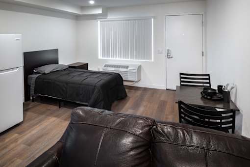 A black bed with a white headboard sits in a room with a brown leather couch.