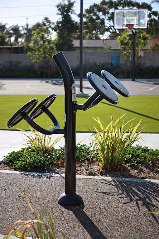 A black sculpture of a person holding a frisbee is in the foreground of a basketball court.