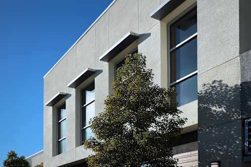 A tree is in front of a building with three windows.