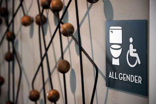 A sign indicating a restroom for all genders is displayed on a wall.
