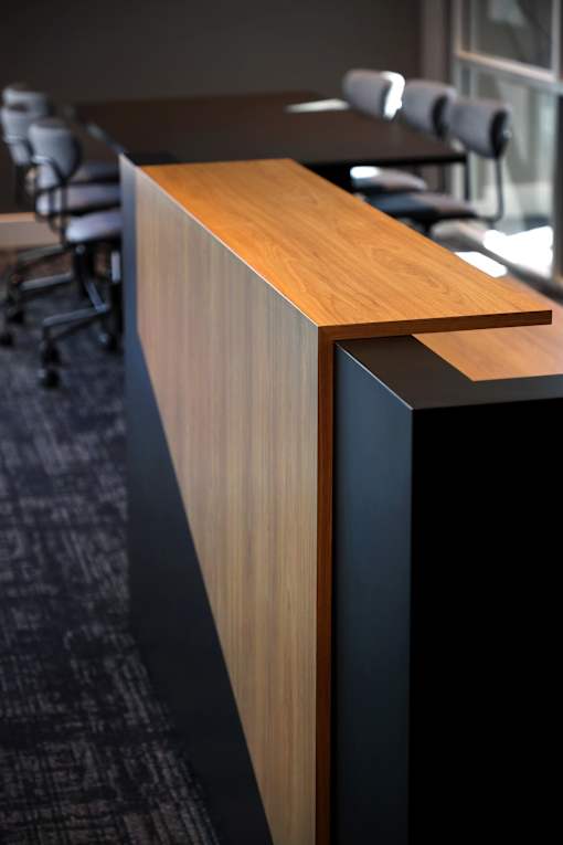 A wooden desk with a black base and a wooden top.