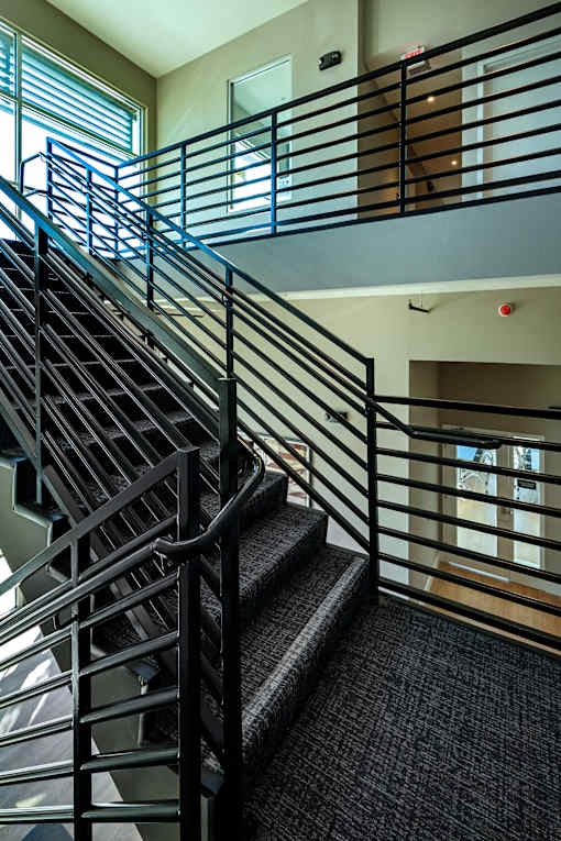 A staircase with a metal railing and steps leading up to a landing with a door.