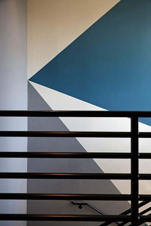 A staircase with a metal railing and a wall with a blue and white design.