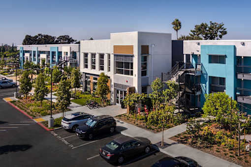 A parking lot with cars and a building with a blue and white facade.