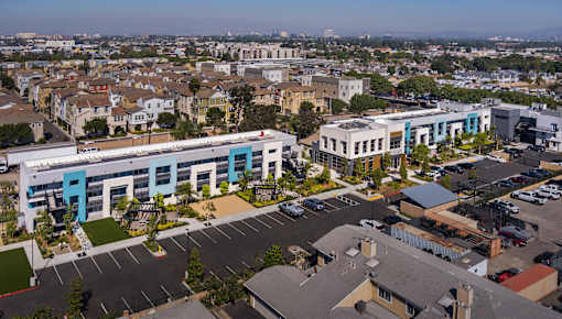 A parking lot in front of a building with a blue and white facade.