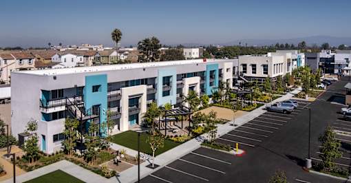 A modern building with a blue and white exterior is surrounded by a parking lot and other buildings.