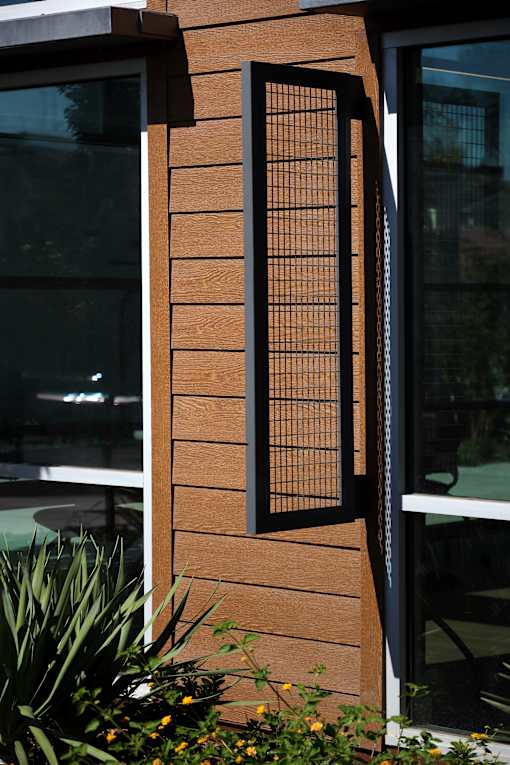 A wooden fence with a black metal grate in the middle.