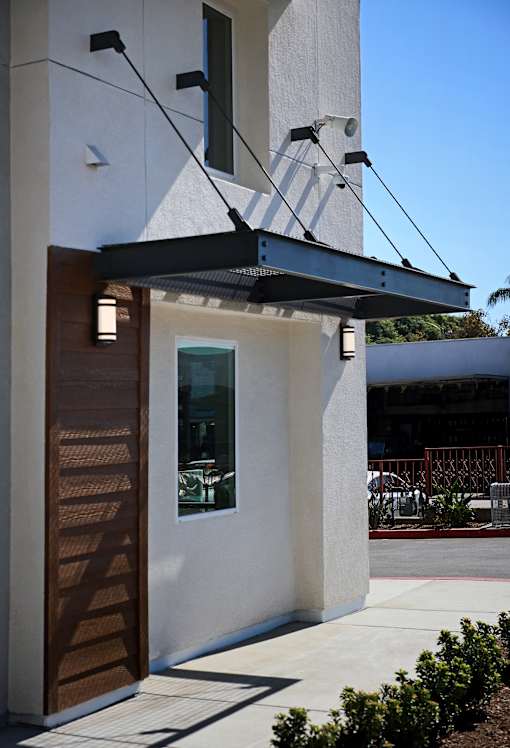A white building with a brown door and a black awning.