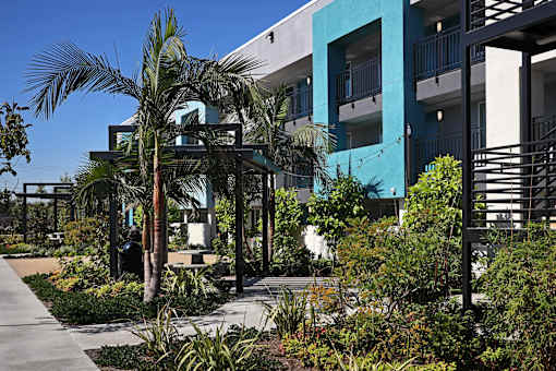 A modern building with a blue and white exterior and a garden in front.