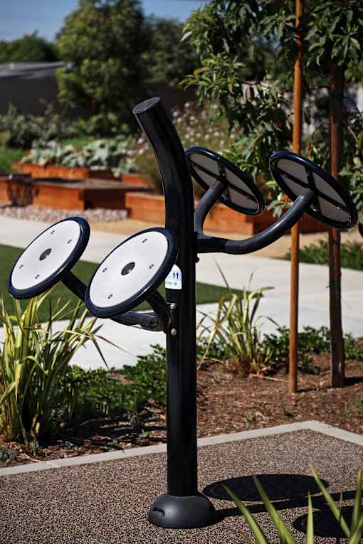 A black outdoor exercise equipment with four circular discs attached to a black pole.