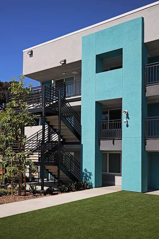 A modern building with a blue and white facade and a staircase leading to the second floor.