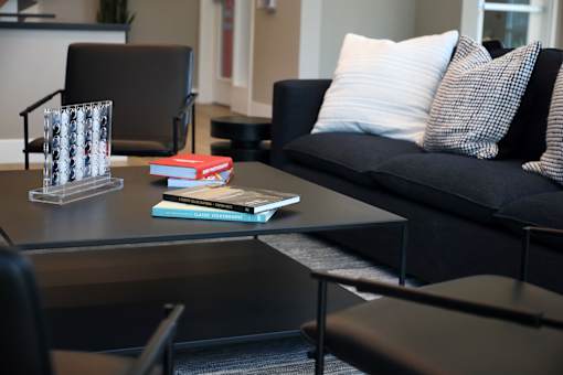 A black couch with a white pillow and a book on a table.